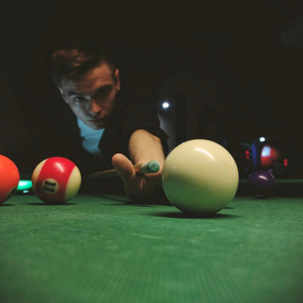 A player aims the cue ball under dim light